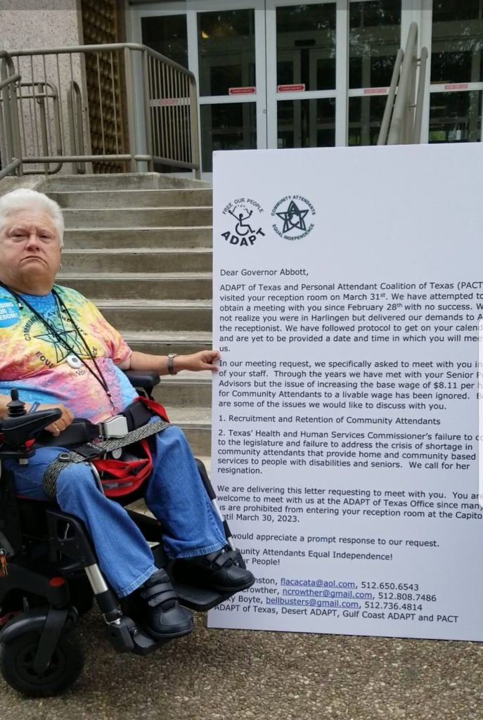 Nancy Crowther sits in front of the Insurance Building stairs holding the GIANT letter to the Gov. She's wearing her tie-dye PACT shirt and a look of determination.   