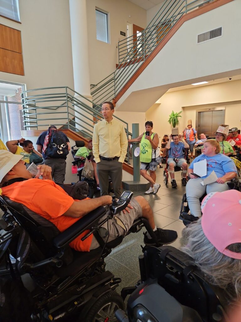 Man speaking to lobby full of ADAPT protesters